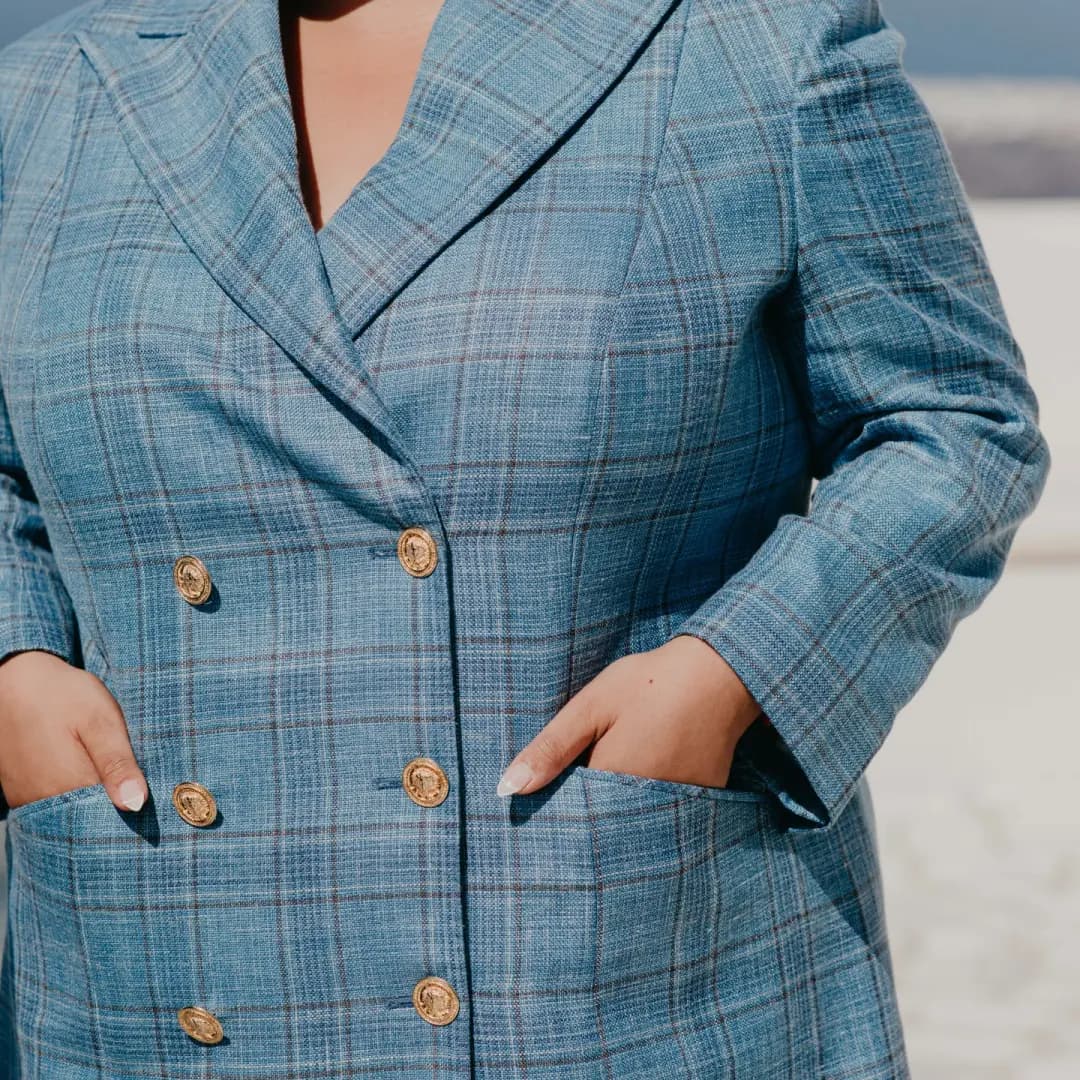 Close view of the blue checked double-breasted long jacket, with gold-coloured buttons and patch pockets