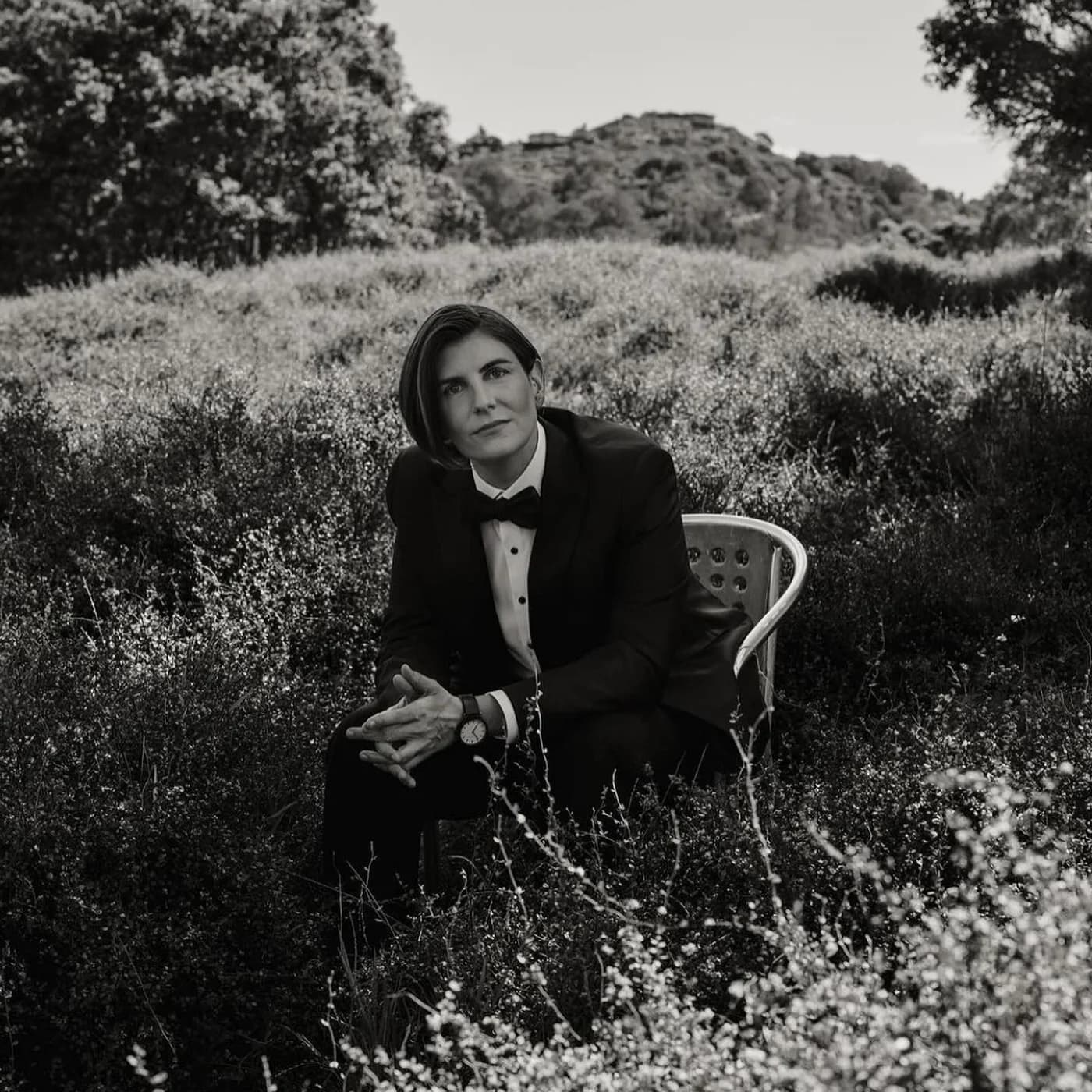 Kim seated outdoors in her wedding tuxedo