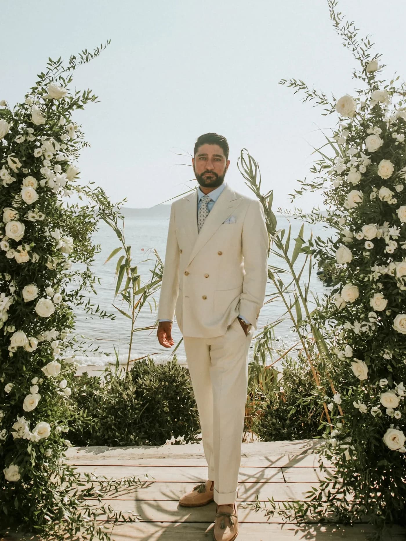 Client wearing a cream double-breasted suit at a seaside wedding