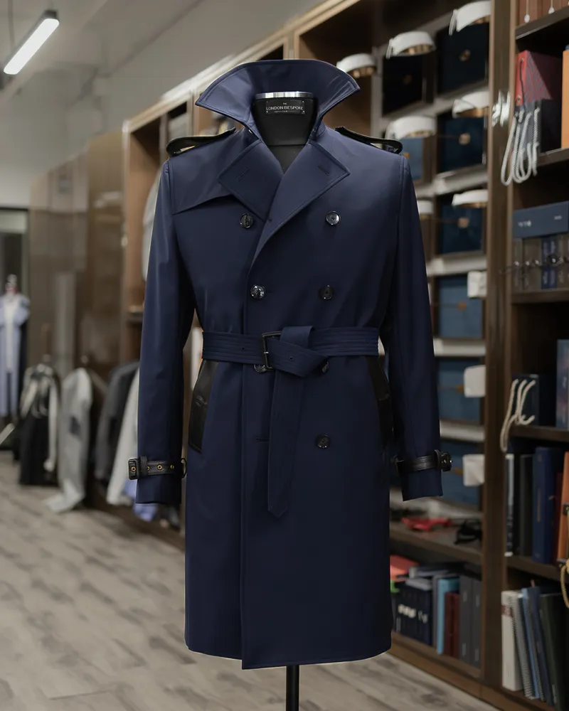 Belted navy trench coat with broad lapels displayed on a mannequin