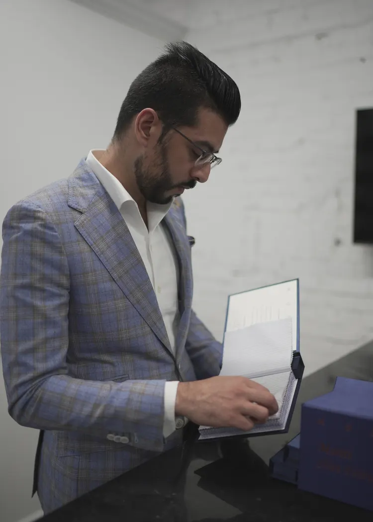 Kunal comparing shirting cloth books at the atelier