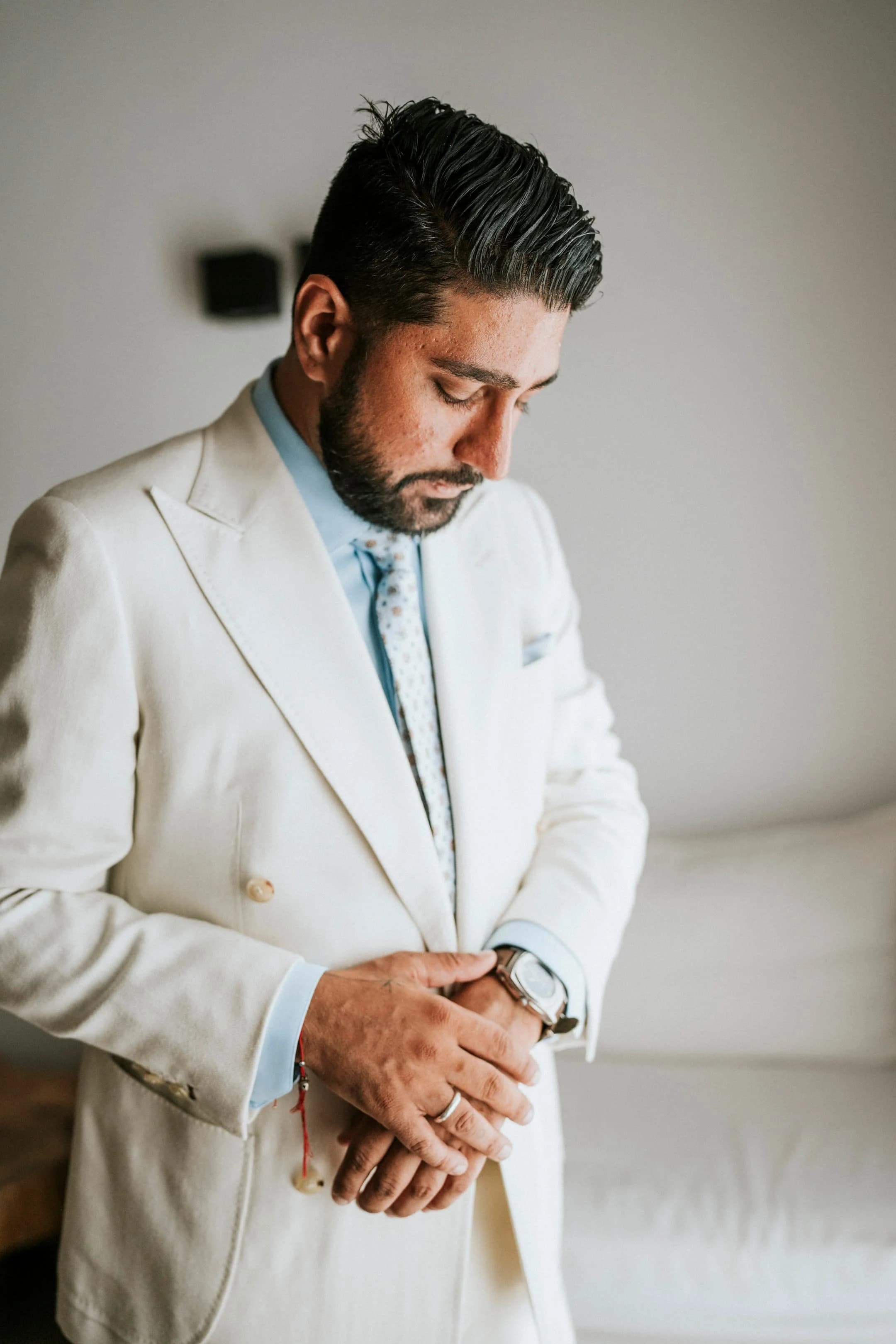 A client adjusting his cuff in an ivory suit