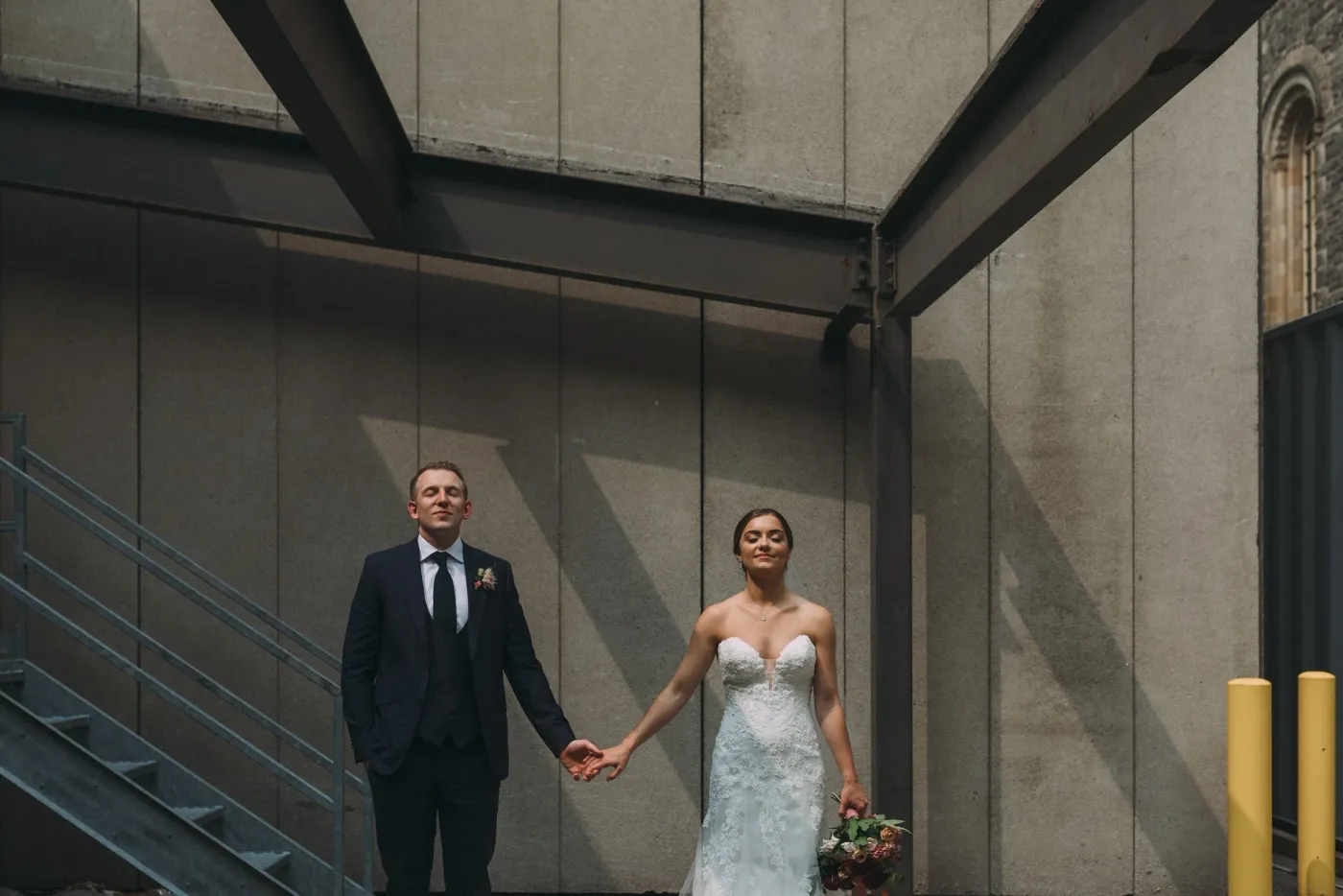 Bride and groom holding hands against an architectural city backdrop