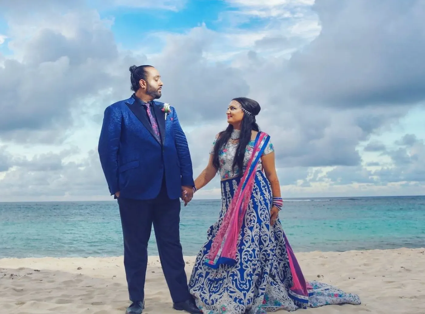 Couple beside the sea, with the groom wearing a blue wedding suit