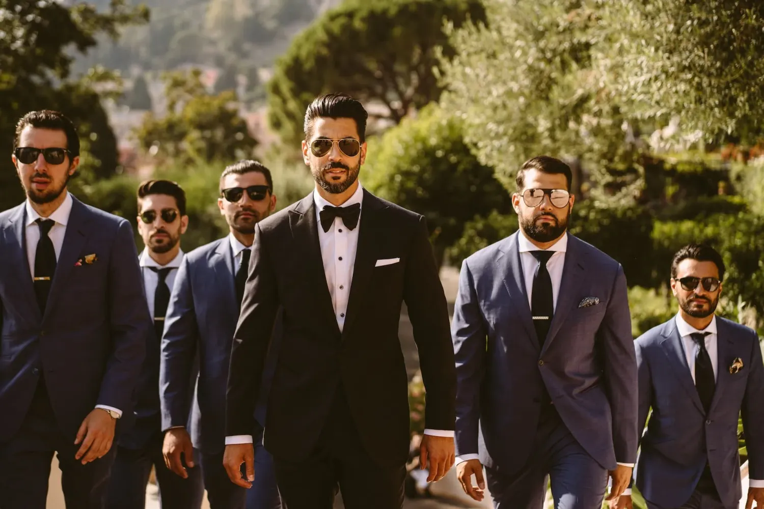 Groom and his wedding party walking together outdoors in tailored suits