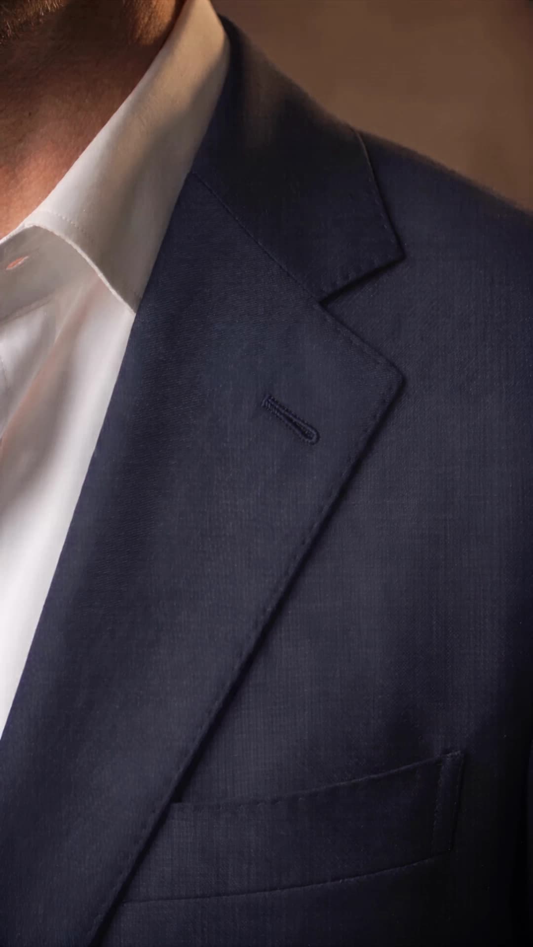 Close view of the navy notch lapel, its soft roll and hand-worked silk buttonhole