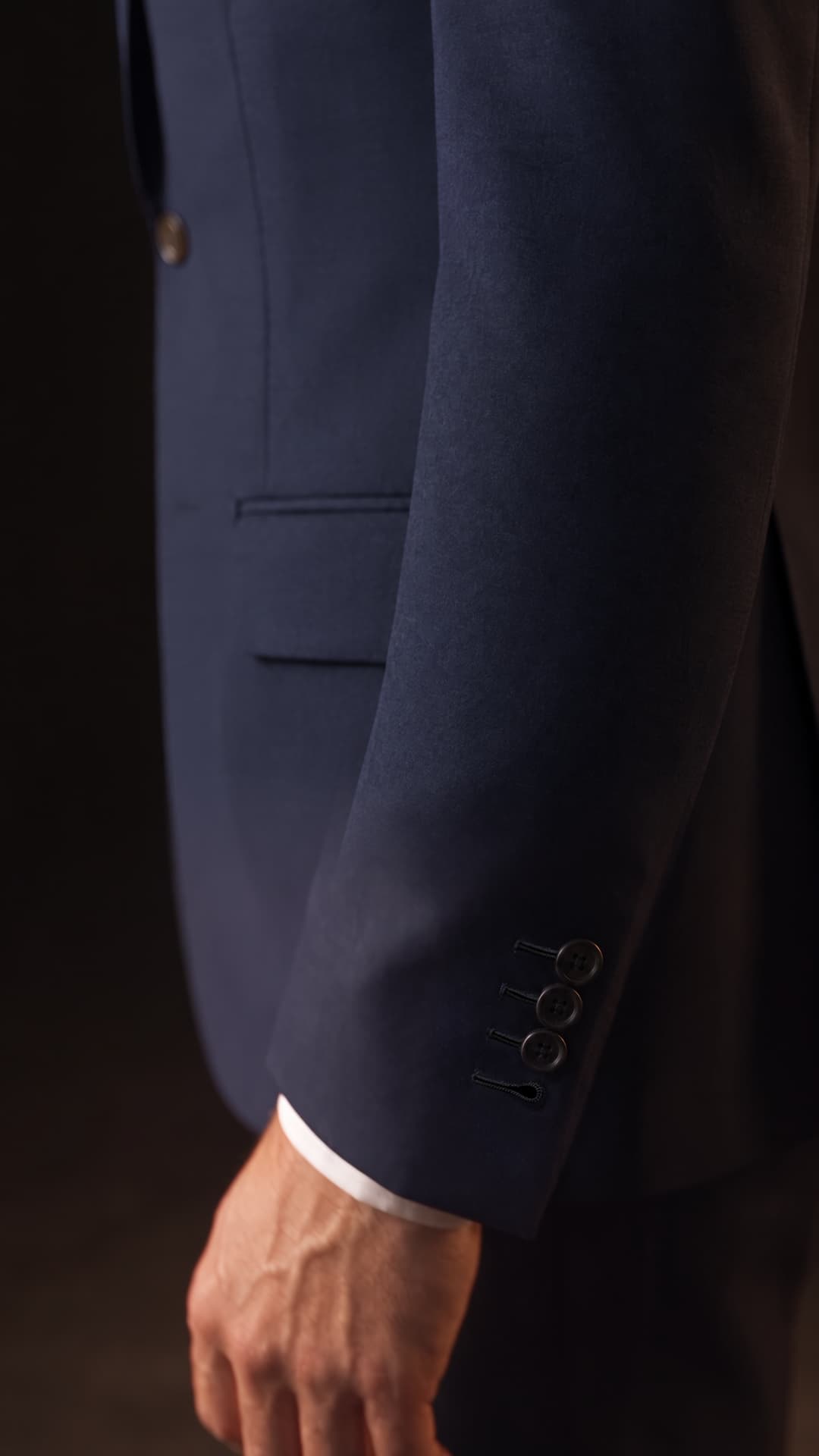 Three fastened navy sleeve buttons above an exposed hand-finished keyhole, with the lowest button removed