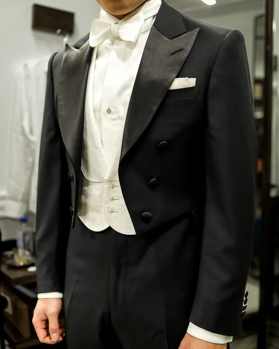 White-tie tailoring with black peak lapels, white waistcoat and bow tie