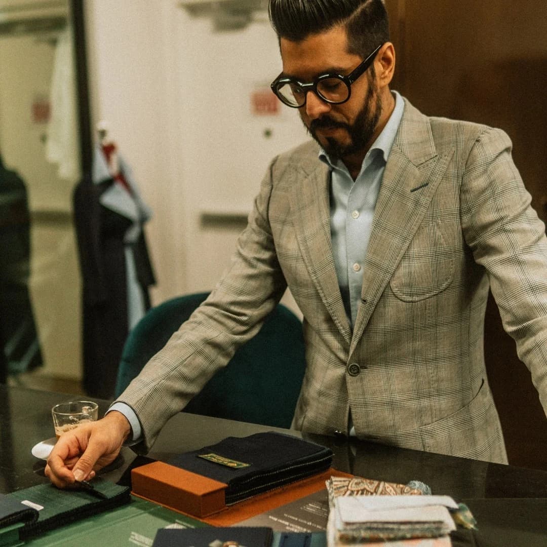 Kunal Arora considering cloth books and swatches at the atelier table