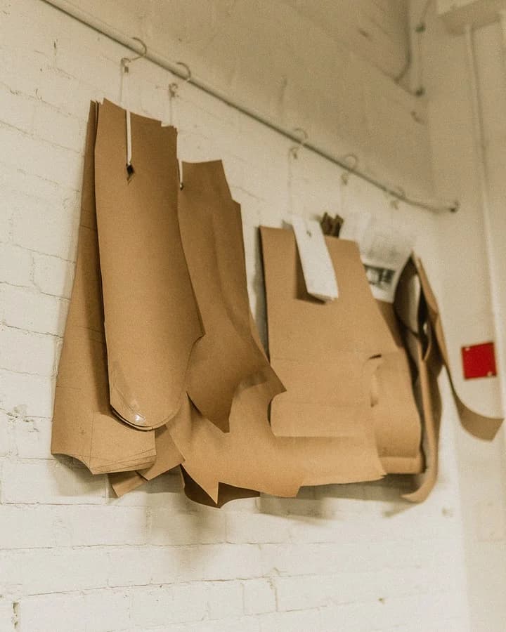 Paper tailoring patterns hanging on the white brick wall at the atelier