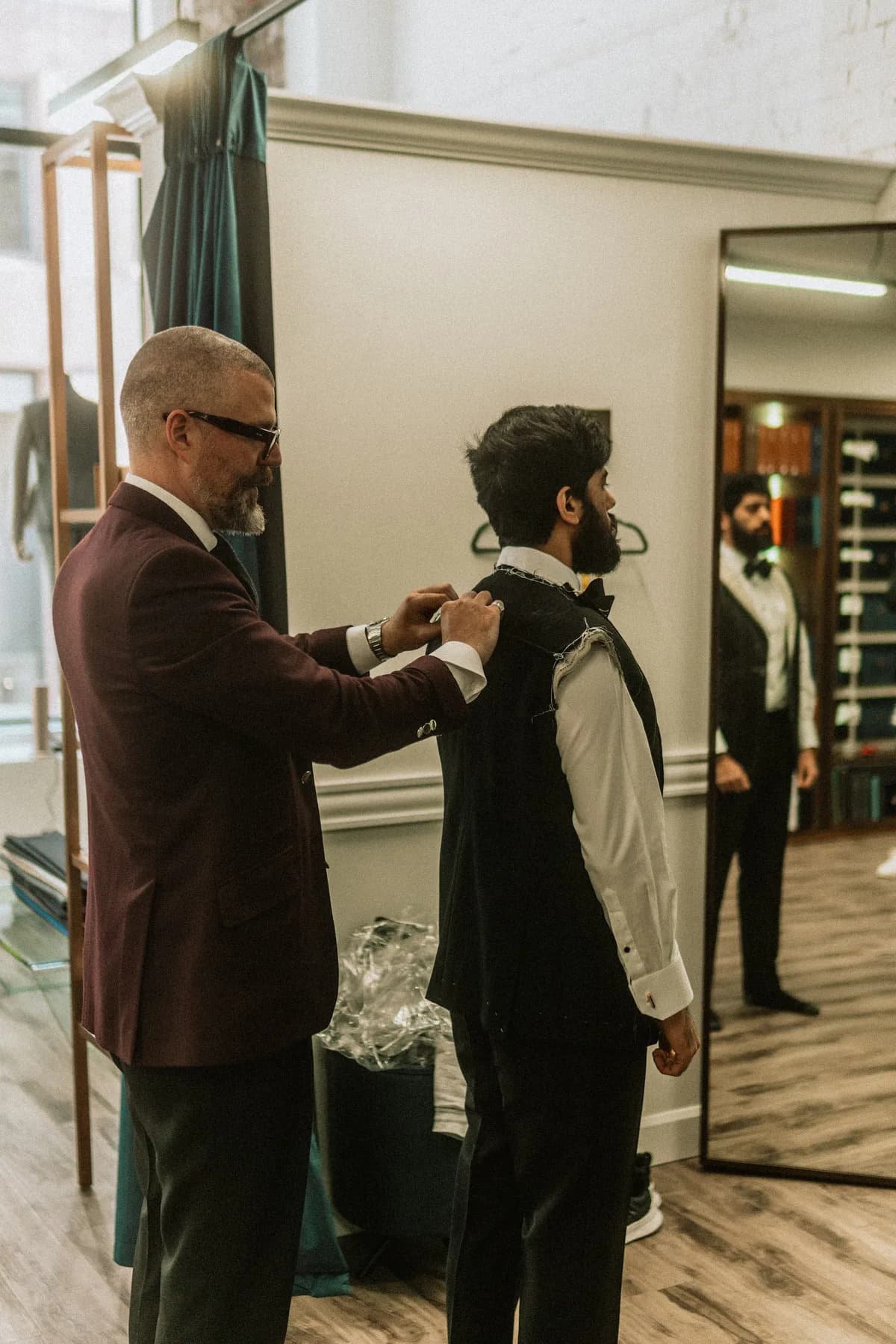 Ian adjusting the shoulder of a basted jacket during a fitting at the atelier
