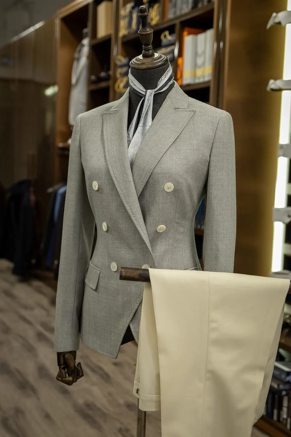 Grey double-breasted women’s jacket styled with ivory trousers at the atelier